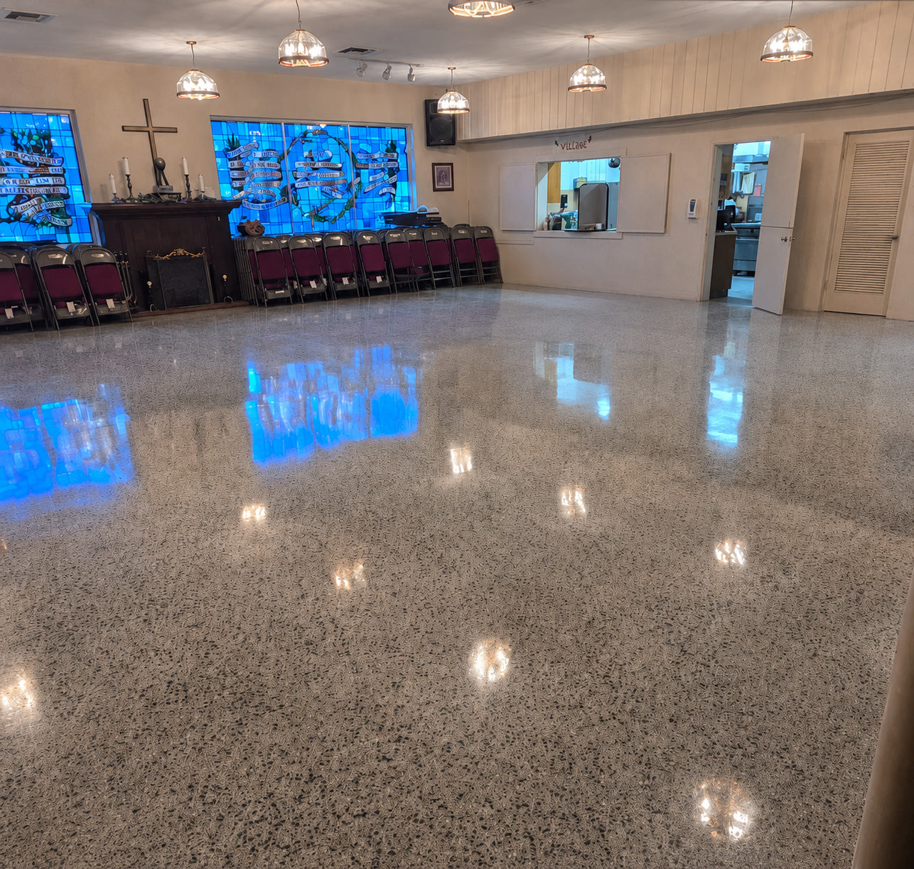Restored terrazzo hall floor with an even polish and clear reflections from the windows and ceiling lights.