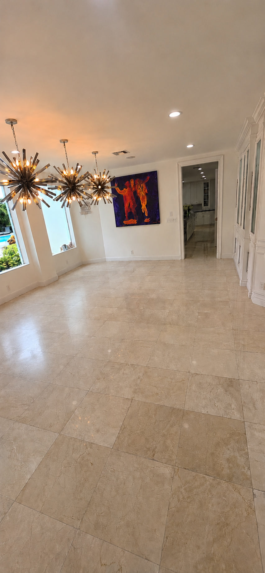 Dining room with a worn cream marble tile floor and soft reflections before polishing.