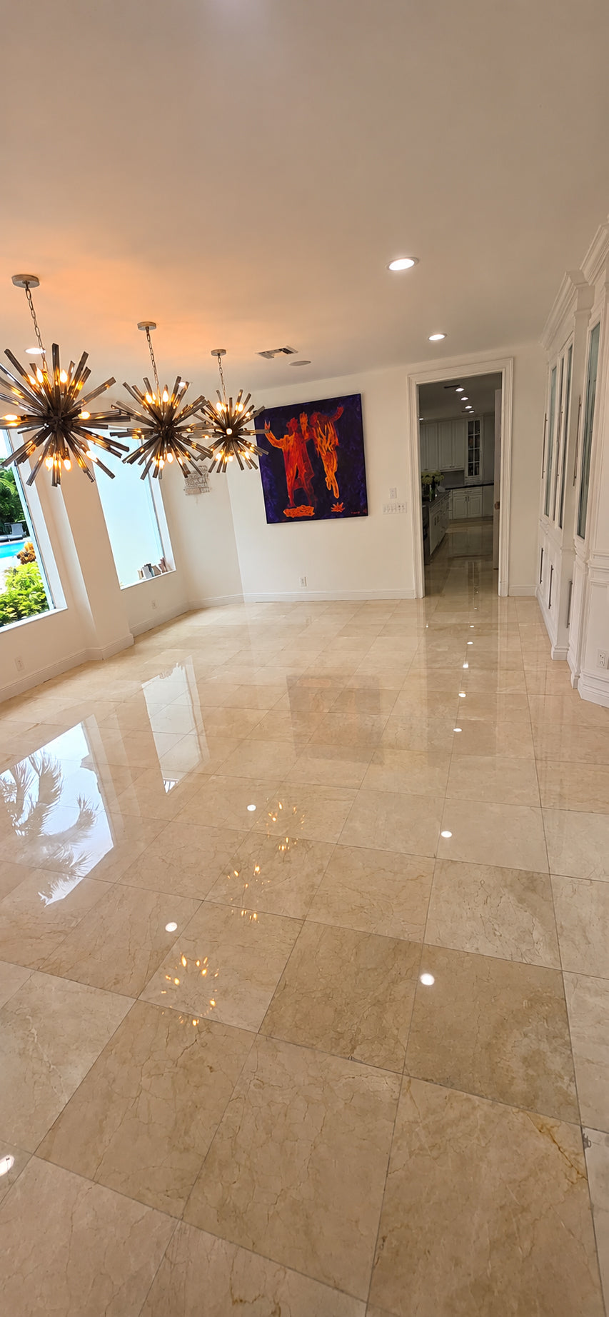 Dining room with a polished cream marble tile floor reflecting the chandeliers after restoration.